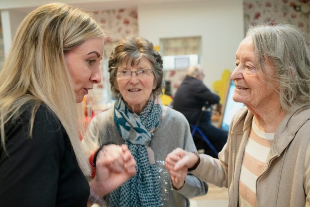 Three women interacting indoors with soft lighting.